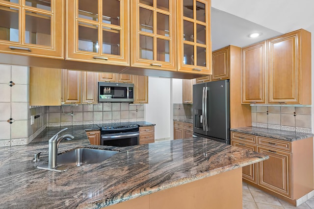 kitchen with light tile patterned flooring, tasteful backsplash, sink, dark stone countertops, and stainless steel appliances