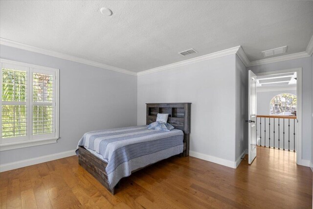 bedroom featuring ornamental molding, connected bathroom, and hardwood / wood-style floors