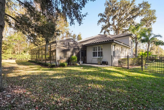 rear view of house with a lanai, a lawn, and a patio