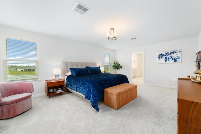 bedroom with connected bathroom, light colored carpet, and a chandelier