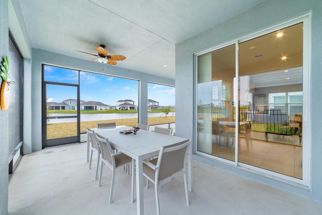 sunroom featuring a water view and ceiling fan