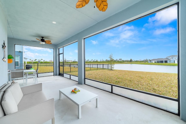 sunroom / solarium featuring ceiling fan and a water view