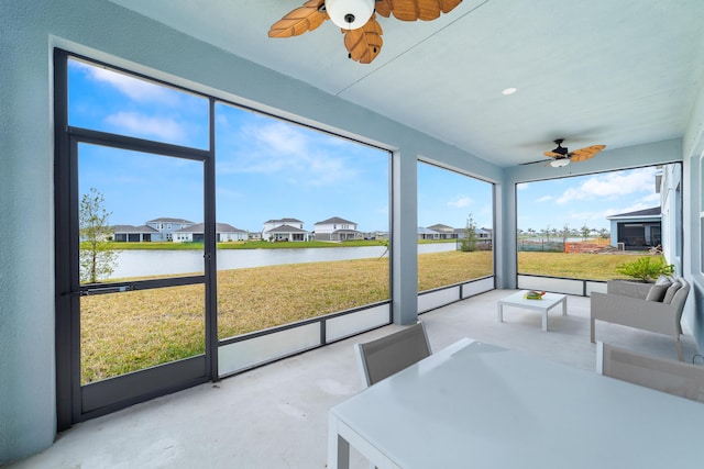 sunroom with a water view, ceiling fan, and a wealth of natural light