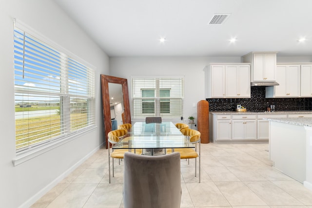 kitchen featuring light tile patterned flooring, light stone countertops, white cabinets, and decorative backsplash