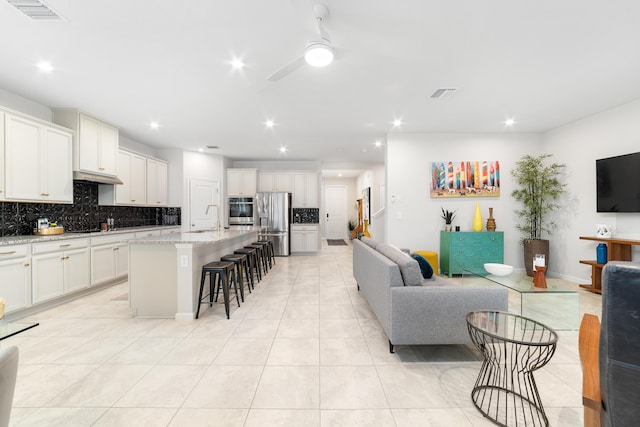 living room with ceiling fan, sink, and light tile patterned floors