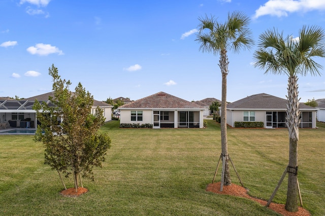 rear view of house with a sunroom and a lawn