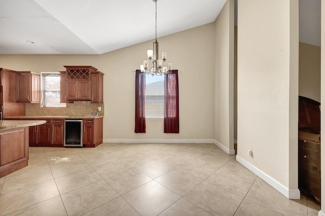 kitchen with wine cooler, light stone counters, decorative backsplash, vaulted ceiling, and decorative light fixtures