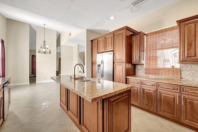 kitchen with stainless steel refrigerator with ice dispenser, light tile patterned flooring, sink, hanging light fixtures, and a kitchen island with sink