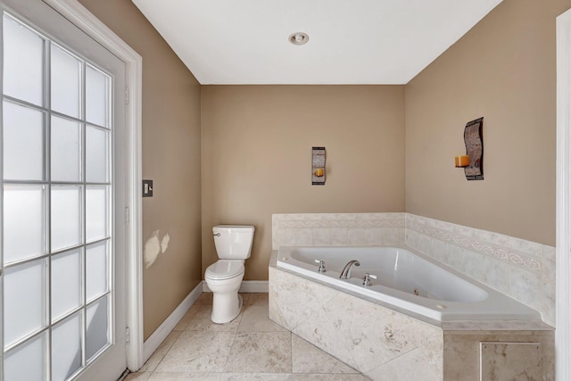 bathroom with a relaxing tiled tub, tile patterned floors, and toilet