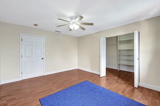 unfurnished bedroom with dark hardwood / wood-style flooring, a spacious closet, and ceiling fan