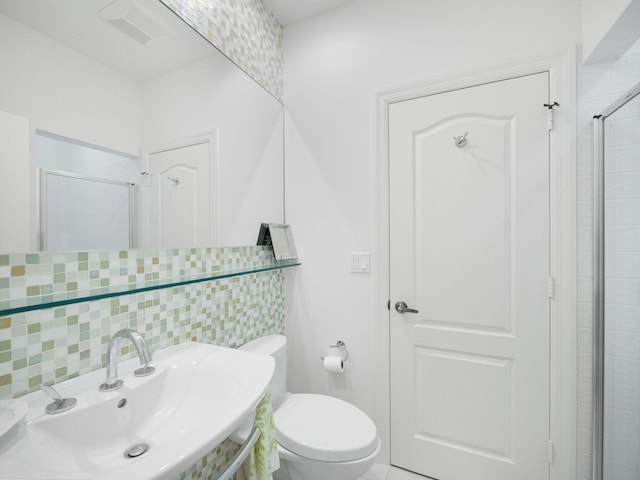 bathroom featuring an enclosed shower, sink, backsplash, and toilet