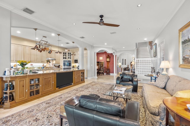 living room with light tile patterned floors, ornamental molding, and ceiling fan