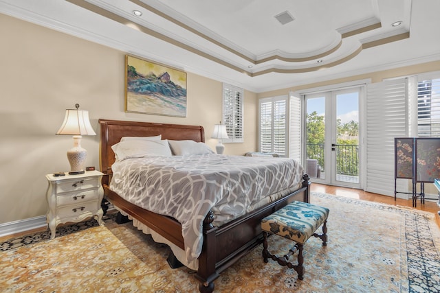 bedroom featuring french doors, ornamental molding, a tray ceiling, hardwood / wood-style flooring, and access to exterior