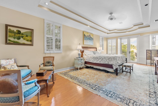 bedroom with a tray ceiling, access to outside, french doors, and hardwood / wood-style flooring