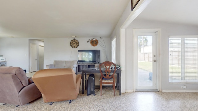 living area featuring speckled floor and baseboards