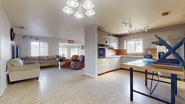 kitchen with stainless steel oven, baseboards, a sink, and white cabinetry