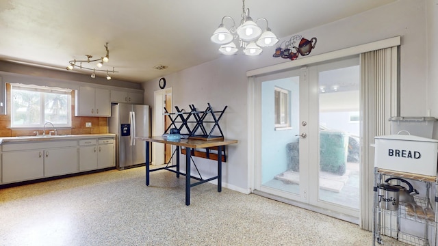 kitchen featuring decorative light fixtures, white cabinetry, sink, backsplash, and stainless steel refrigerator with ice dispenser