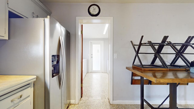 corridor featuring light speckled floor and baseboards