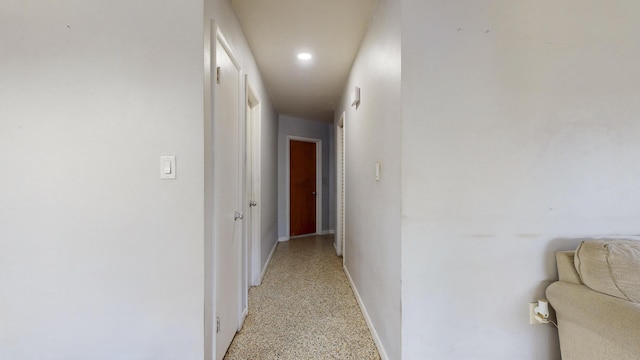 hallway with baseboards, light speckled floor, and recessed lighting