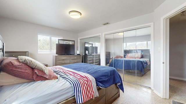 bedroom featuring light speckled floor, multiple closets, visible vents, and baseboards
