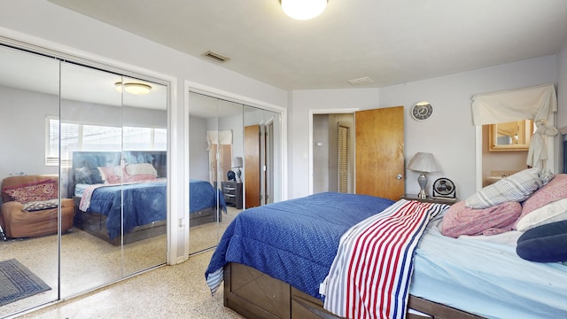 bedroom with multiple closets, visible vents, and speckled floor