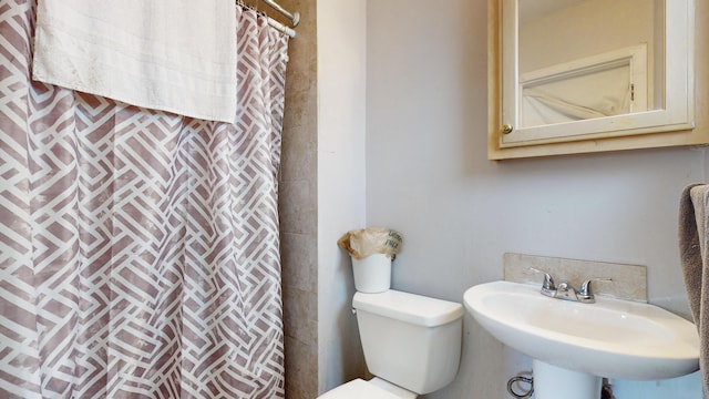 bathroom featuring a shower with shower curtain, toilet, and a sink