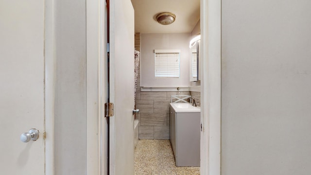 bathroom featuring tile walls, vanity, and speckled floor