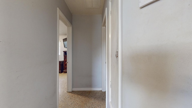 corridor featuring speckled floor, baseboards, and visible vents