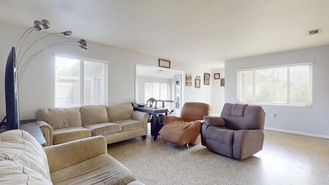 living room featuring baseboards, visible vents, and speckled floor