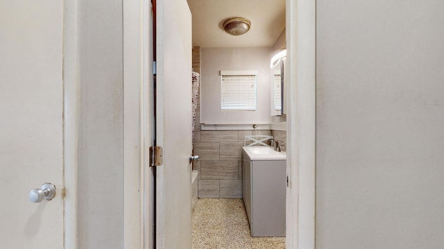 bathroom featuring vanity and tile walls