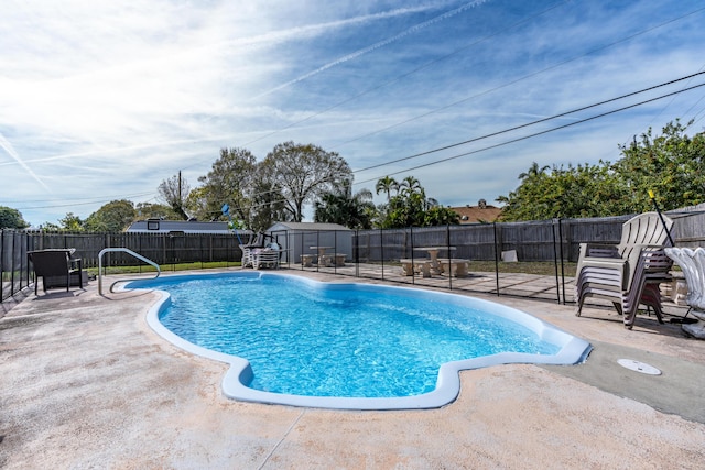 view of swimming pool with a fenced backyard, a patio, and a storage unit