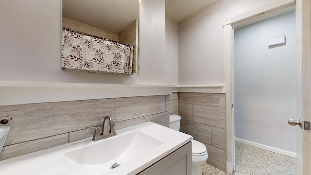 bathroom featuring vanity, toilet, and tile walls