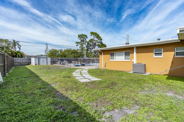view of yard featuring central AC, a patio area, a fenced backyard, an outbuilding, and a storage unit
