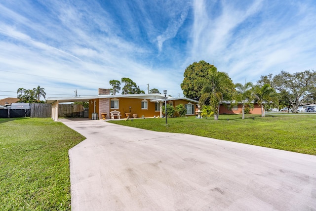 ranch-style house with an attached carport, a chimney, concrete driveway, fence, and a front yard