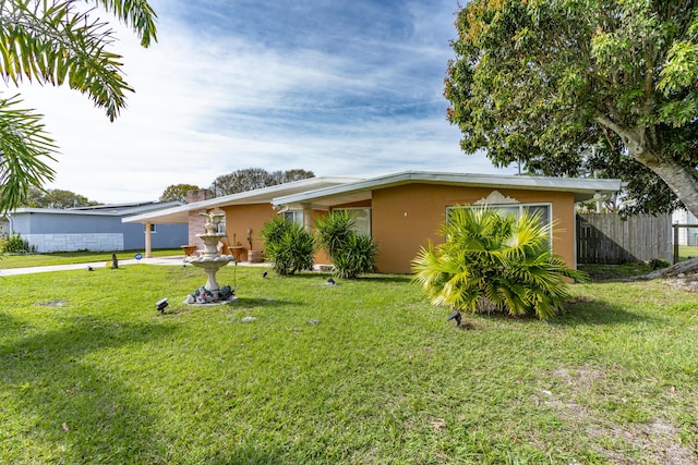 view of front of home with stucco siding, a front yard, and fence