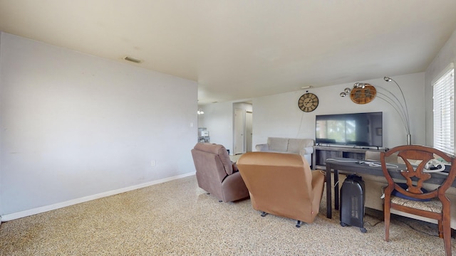 living area with light speckled floor, visible vents, and baseboards