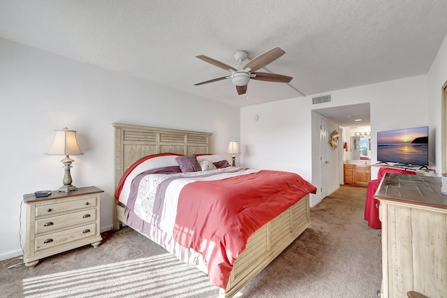 bedroom featuring ceiling fan, ensuite bathroom, carpet flooring, and a textured ceiling