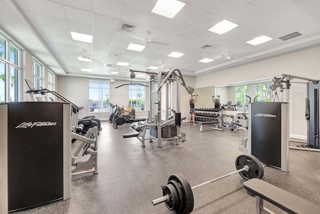 exercise room featuring a paneled ceiling and a wealth of natural light