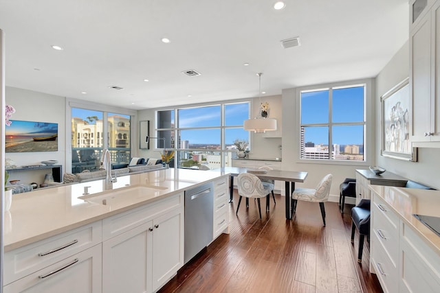 kitchen featuring sink, white cabinetry, stainless steel dishwasher, dark hardwood / wood-style flooring, and pendant lighting