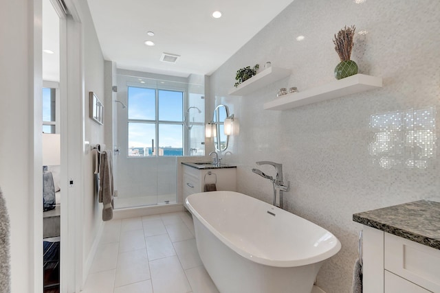 bathroom with vanity, plus walk in shower, tile patterned flooring, and tile walls