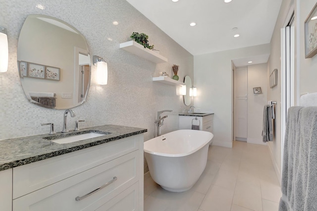 bathroom with a washtub, vanity, and tile patterned flooring