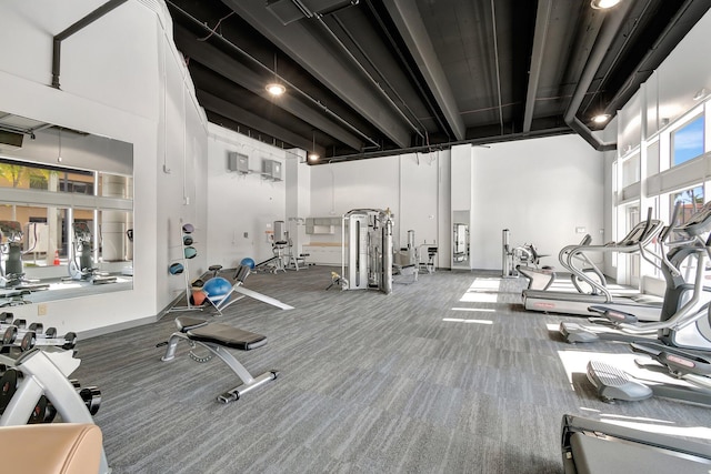 exercise room with carpet and a towering ceiling