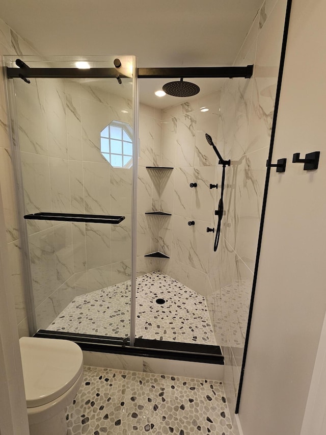 bathroom featuring a shower with shower door and toilet