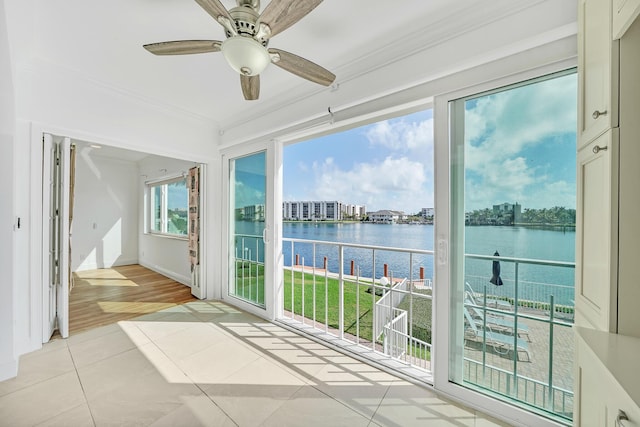 unfurnished sunroom featuring a water view and ceiling fan