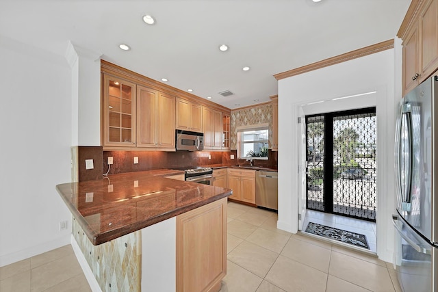 kitchen featuring a peninsula, light tile patterned floors, glass insert cabinets, and stainless steel appliances