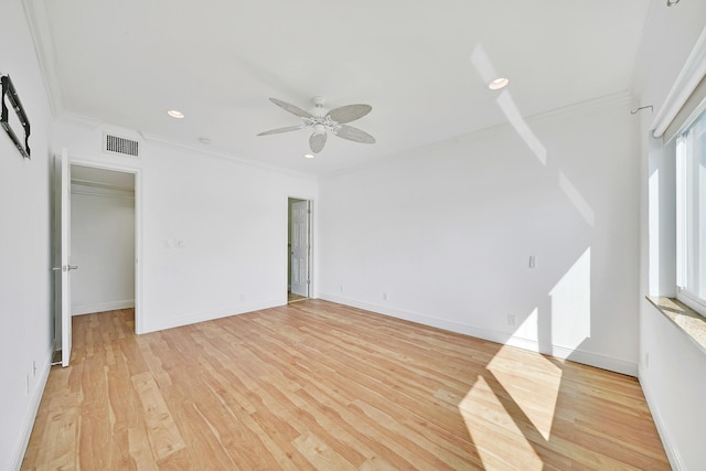 spare room featuring baseboards, visible vents, crown molding, and light wood finished floors