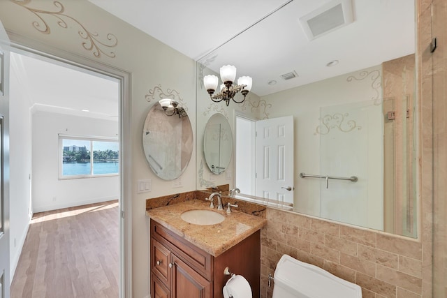 bathroom with a chandelier, visible vents, vanity, and toilet