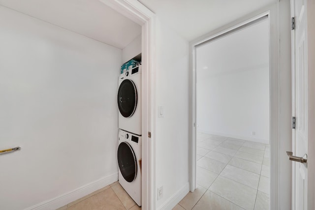 washroom featuring light tile patterned floors, laundry area, baseboards, and stacked washer / drying machine