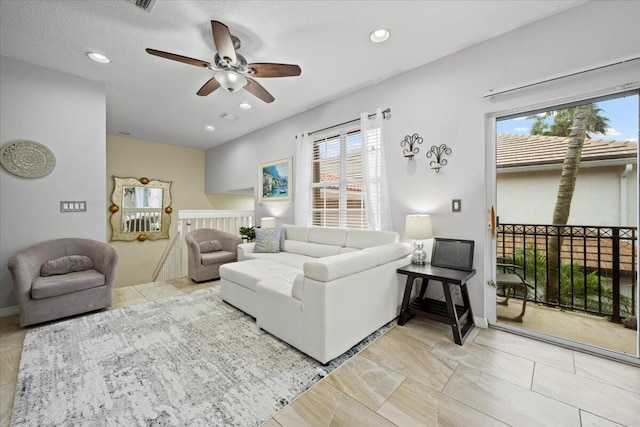 living room with ceiling fan and a textured ceiling