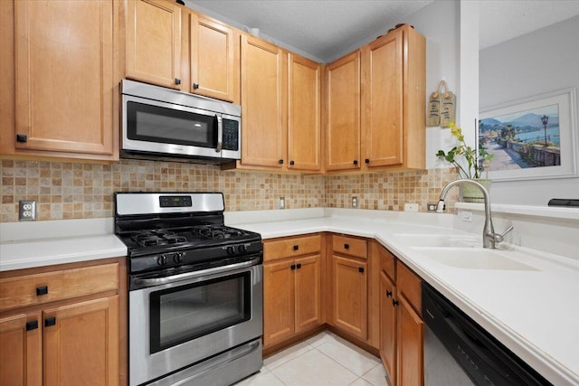 kitchen with light tile patterned flooring, appliances with stainless steel finishes, sink, and backsplash